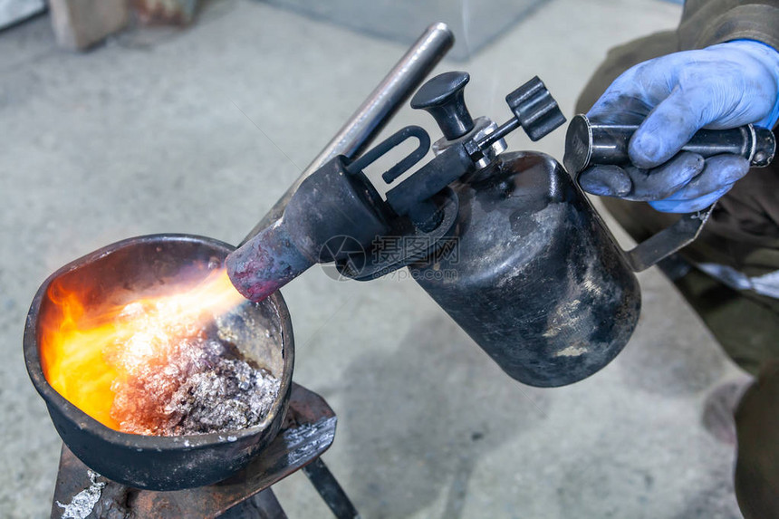 使用气炬熔化铅金属的专业男工用火直接瞄准熔融金属的燃气烧图片