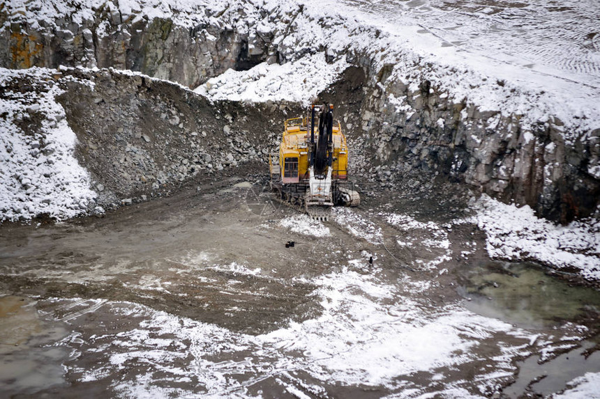 巨大的黄色挖掘机在冬季花岗岩采石场图片