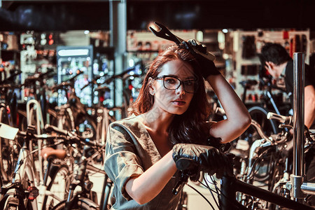 年轻有吸引力的工人在车间修理顾客自行车图片