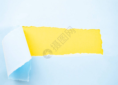 在黄色上隔离的撕破的粉彩蓝纸图片