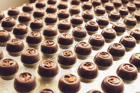 黑巧克力糖果以特殊形状排列在行内手工制做的巧克力有选择的焦点水平框背景图片