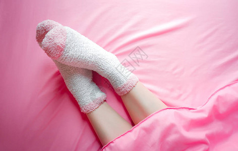 冬天早上穿袜子的妇女和毛毯背景床单上暖图片