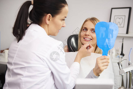 在牙科检查期间检查该妇女牙齿图片