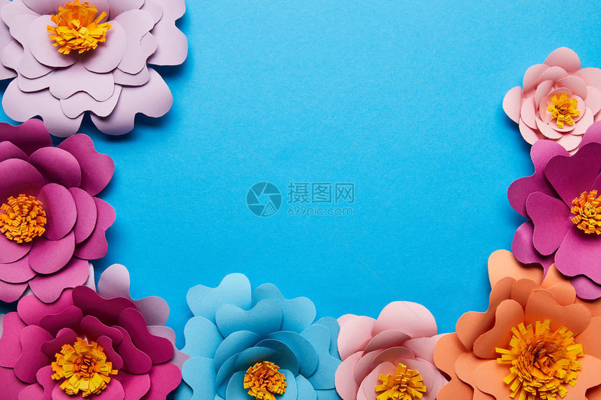 蓝色背景上彩色剪切纸花的顶部视图片