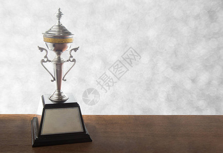 Bokeh背景的木桌上的银奖杯复制背景图片