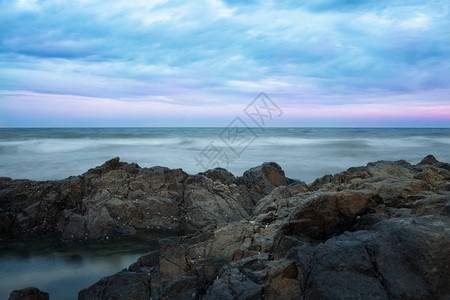 日落背景下的暴风雨海洋和石质海岸图片