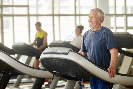 一位老人正在健身快乐的老人在健身房的跑步机上图片