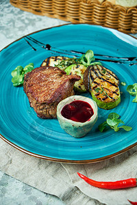 牛排加烧烤蔬菜和林边莓酱蓝色盘图片