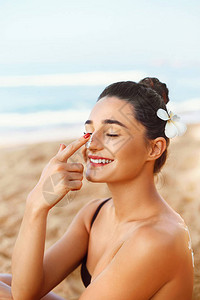 防晒霜晒黑乳液美丽的女人应用在美丽的脸上防晒霜皮肤护理防晒女孩使图片