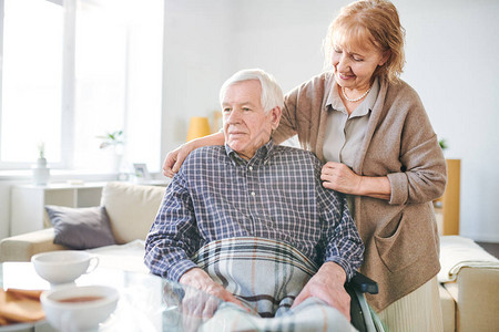 快乐的年长妇女照顾其老年残疾丈夫在轮椅图片
