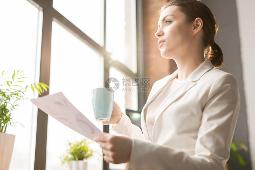 年轻的笔记分析师或身穿正式服装的经济学家在喝茶和思考数据时图片