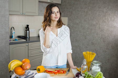 一个穿着白衬衫的年轻美女在厨房里假扮着在图片