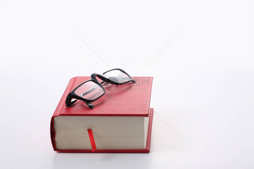 在白背景上隔离的红色书和眼镜并有文图片