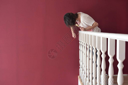 年轻漂亮的女人用刷子画一个窗台栏杆白色背景图片