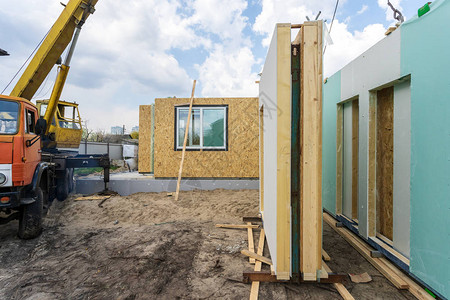 从复合sip面板建造新的现代模块化房屋的过程站在新建筑和起重机附图片