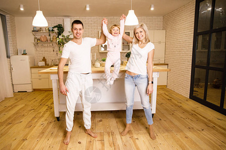 美丽的家庭爸妈和女儿在明亮公寓的厨图片