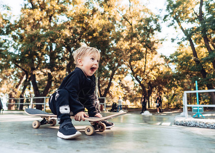 小男孩有滑板小孩子坐在公园里图片
