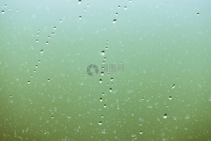 有雨滴的脏玻璃绿色清晰散景背上的雨滴窗外绿意盎然水滴和污渍关闭宏中详图片