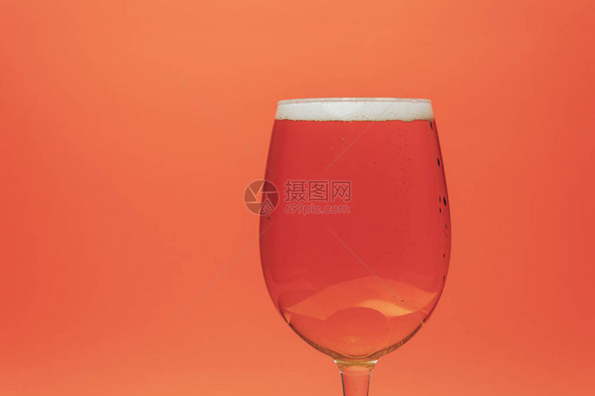 珊瑚橙背景上的玻璃啤酒图片