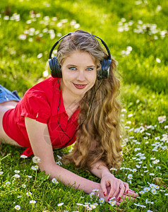 听耳机的女孩在绿色草地上捕捉节奏音乐图片