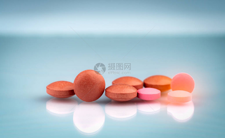 灰色背景上的圆形橙色和粉红色药片医药行业医院和日常生活中的药物使用于偏关节炎压力图片