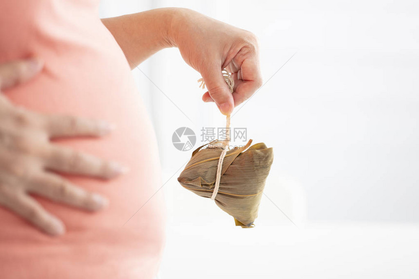 拿着传统粽子和大肚皮的手图片