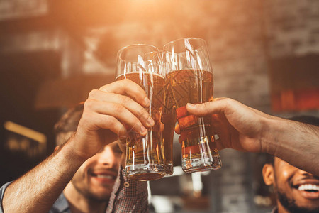 在酒吧喝啤酒和将玻璃合在一起的男子饮酒图片