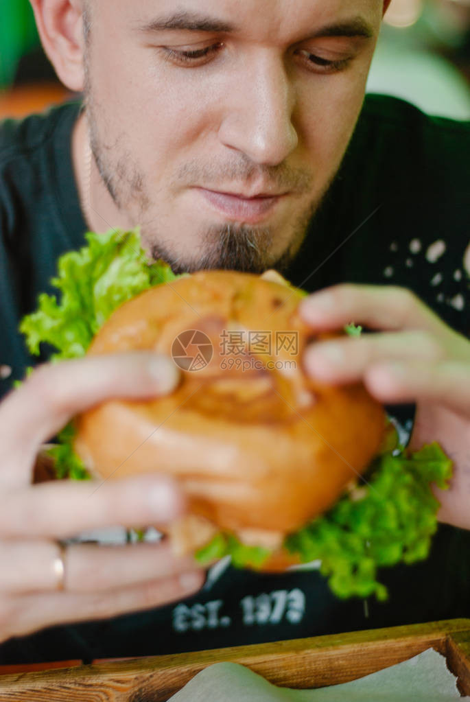 餐馆里的人吃汉堡包他饿了吃着好吃的口图片