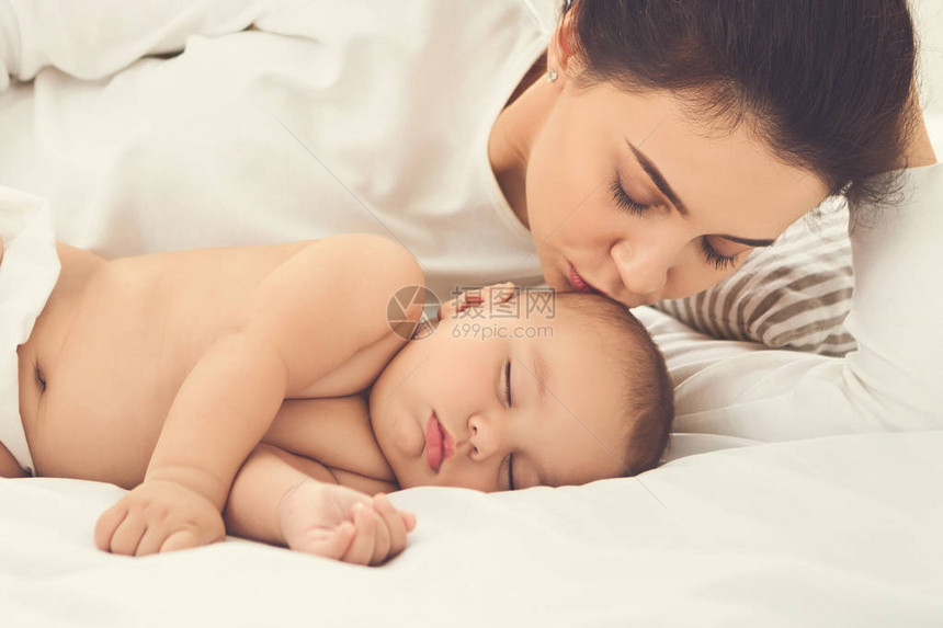 年轻母亲吻她睡着的新生儿婴图片