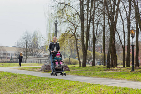 年轻妈带着婴儿在婴儿车里散步图片
