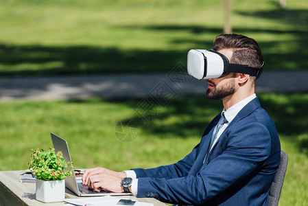 青年商人坐在公园VR头盔时使高清图片