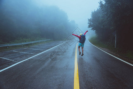 亚洲女旅行自然走在公路线上愉快地旅行自然雾雨中泰图片