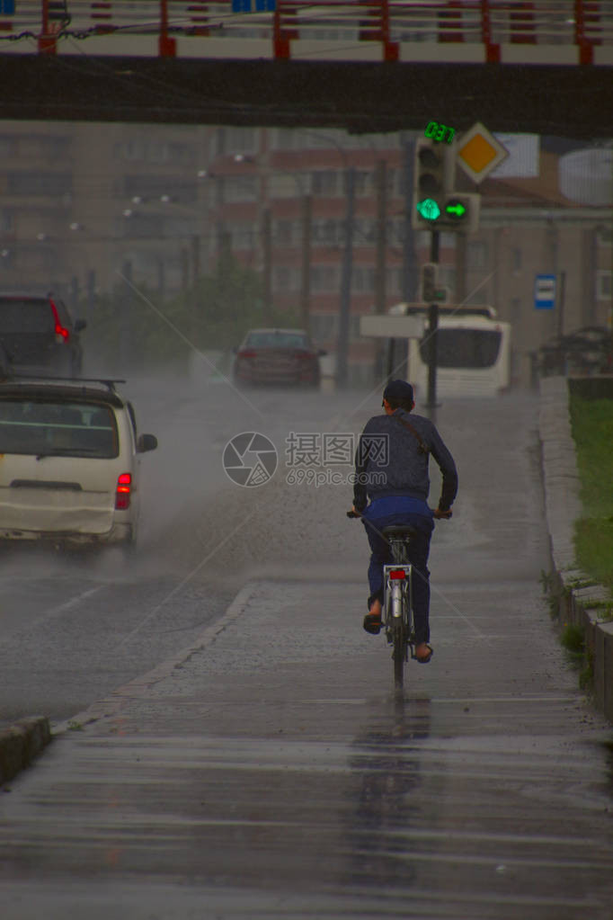 男子在雨中骑自行车在汽图片