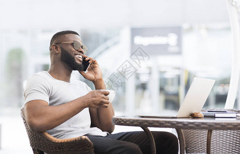 坐在网吧喝咖啡讲电话全景的非洲帅美男子图片