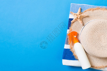 夏日沙滩平面套件遮阳玻璃瓶奶油草帽毛巾和彩色背景的贝壳旅行假期概图片