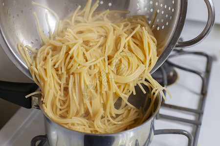 将煮熟和沥干的意大利面倒入沸腾的锅中图片