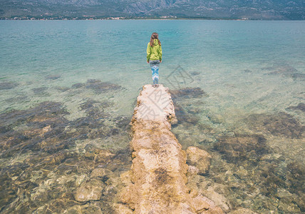 一个女人站在石墩上女孩看着海水克罗地亚的假期图片