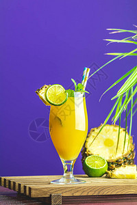 用挤压菠萝汁石灰和薄荷的冰冷鸡尾酒在紫罗兰背景的高杯里夏季饮料图片