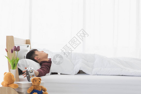 躺在床上的亚洲帅哥然后醒来因为他的闹钟在卧图片