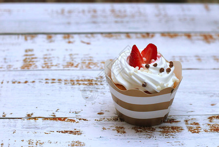 烤奶油蛋糕鲜草莓和巧克力球在旧白木制桌底图片