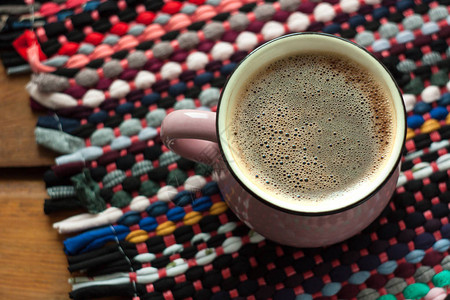 杯咖啡木制背景与纺织手工编织的抹布地毯图片