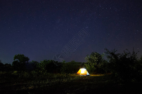 在充满星的美丽夜空下露营帐篷繁星点的夜空在大自然中被照亮的图片
