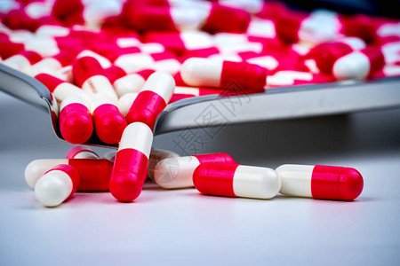 药物托盘上的红白色胶囊丸和一些在白色桌子上药房店背景药剂学概念医药行业医药产品用于口服背景图片