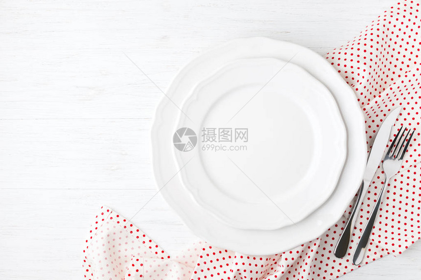 Polka点纸巾上的白色空板和餐具图片