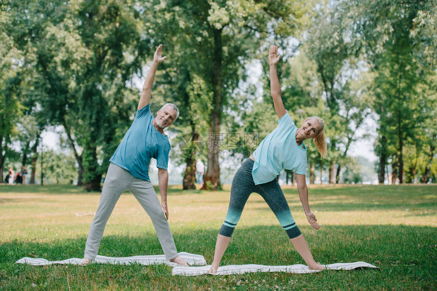 在公园的瑜伽垫子上站着时做武士瑜伽姿势的成图片