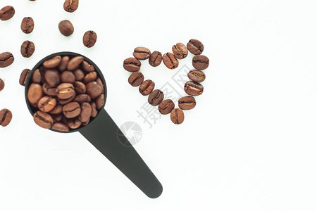 棕色烤咖啡豆在黑色量匙和孤立的白色背景上的豆心有选择地专注于心脏茶歇图片