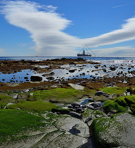 低潮时多彩的岩石海岸海湾石油钻井机和蓝色天空图片
