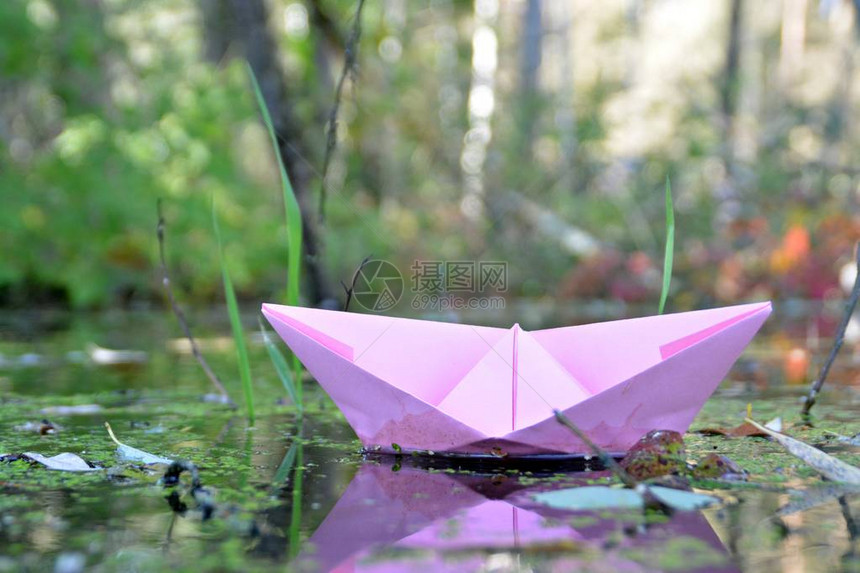 纸船在低流水中漂浮在秋叶之间图片