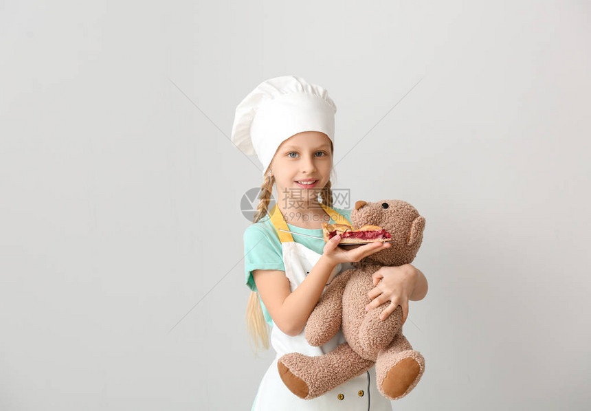 可爱的小厨师喂小玩具熊用图片