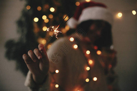 戴着圣诞帽的时尚髦女孩手里燃烧着大烟火新年快乐的气氛圣诞节快图片